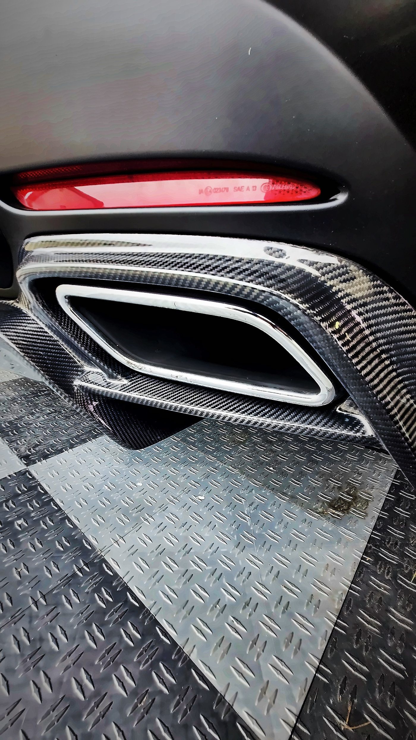 Carbon fiber rear diffuser and chrome exhaust tip under a red rear reflector