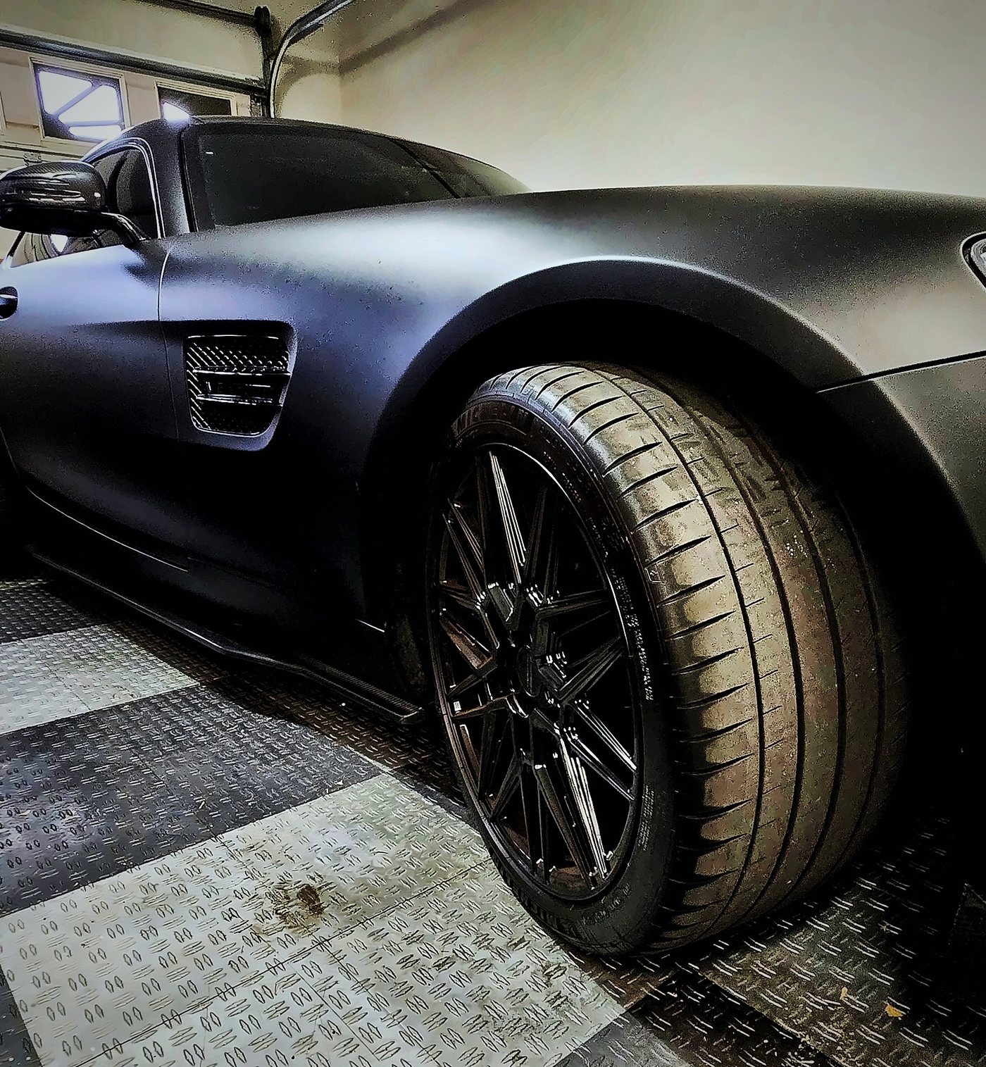 Low angle of the AMG GT S front fender, side vent, carbon fiber side skirt and gloss black Vossen wheel