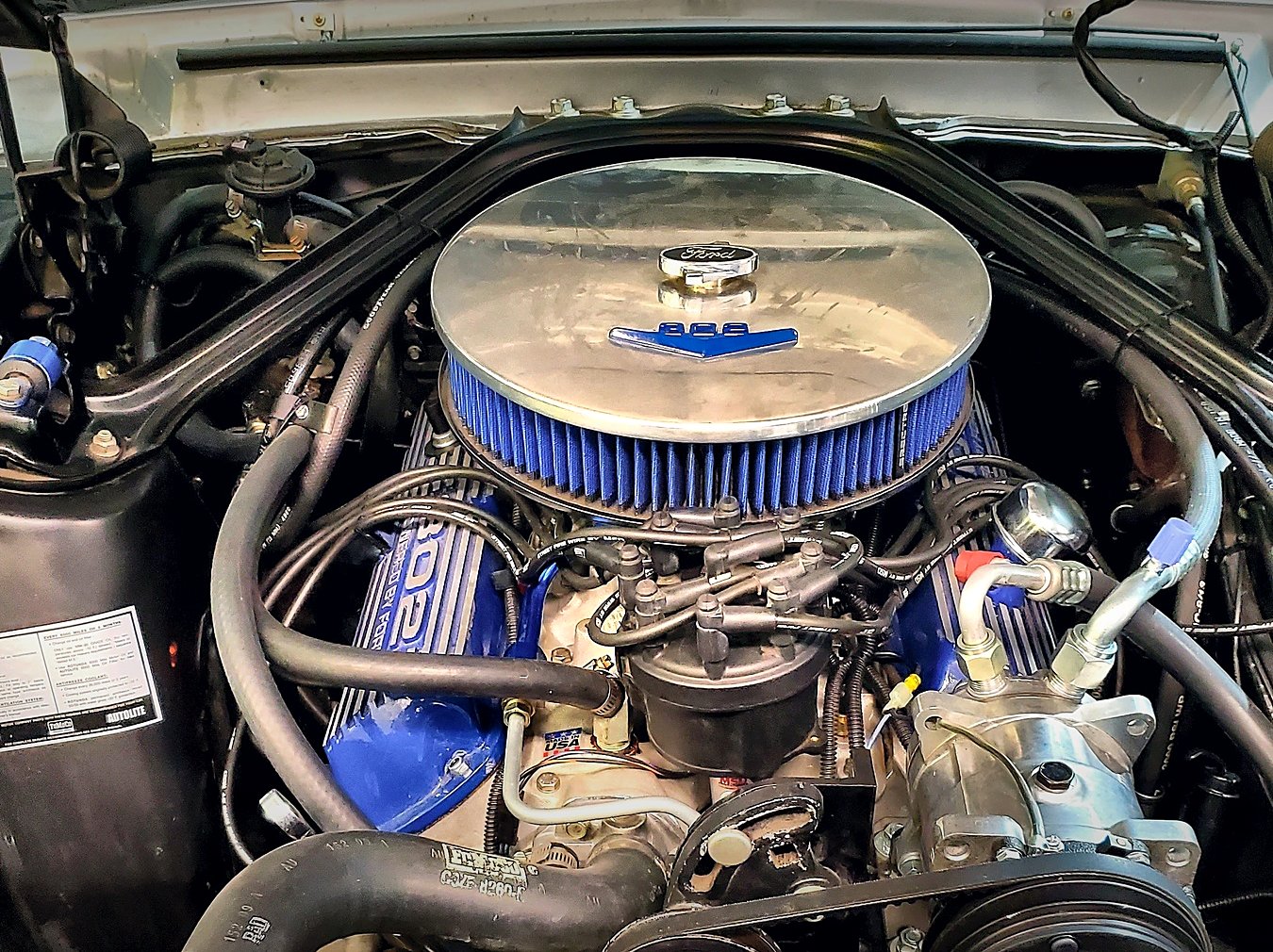 The Mustang’s 332 stroker V8 with blue Ford valve covers, chrome air cleaner and Holley carburetor